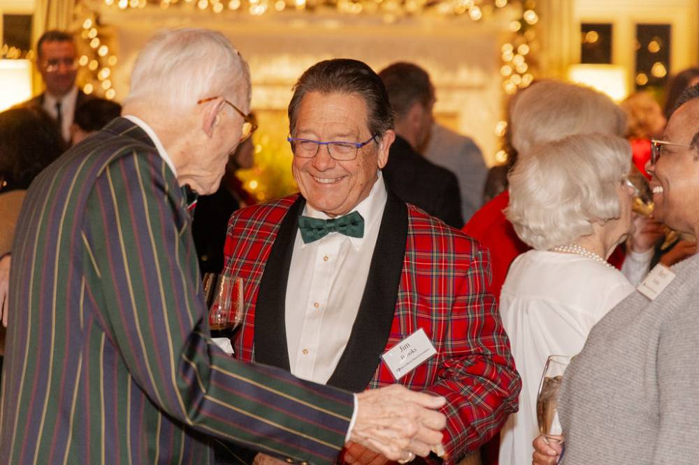 Jim Brooks in festive blazer greeting other reception guest